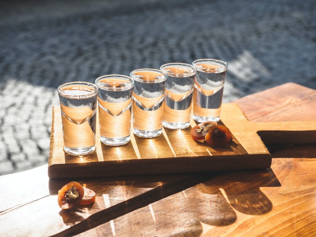 close-up view of glasses with chacha and delicious traditional sliced churchkhela on wooden table