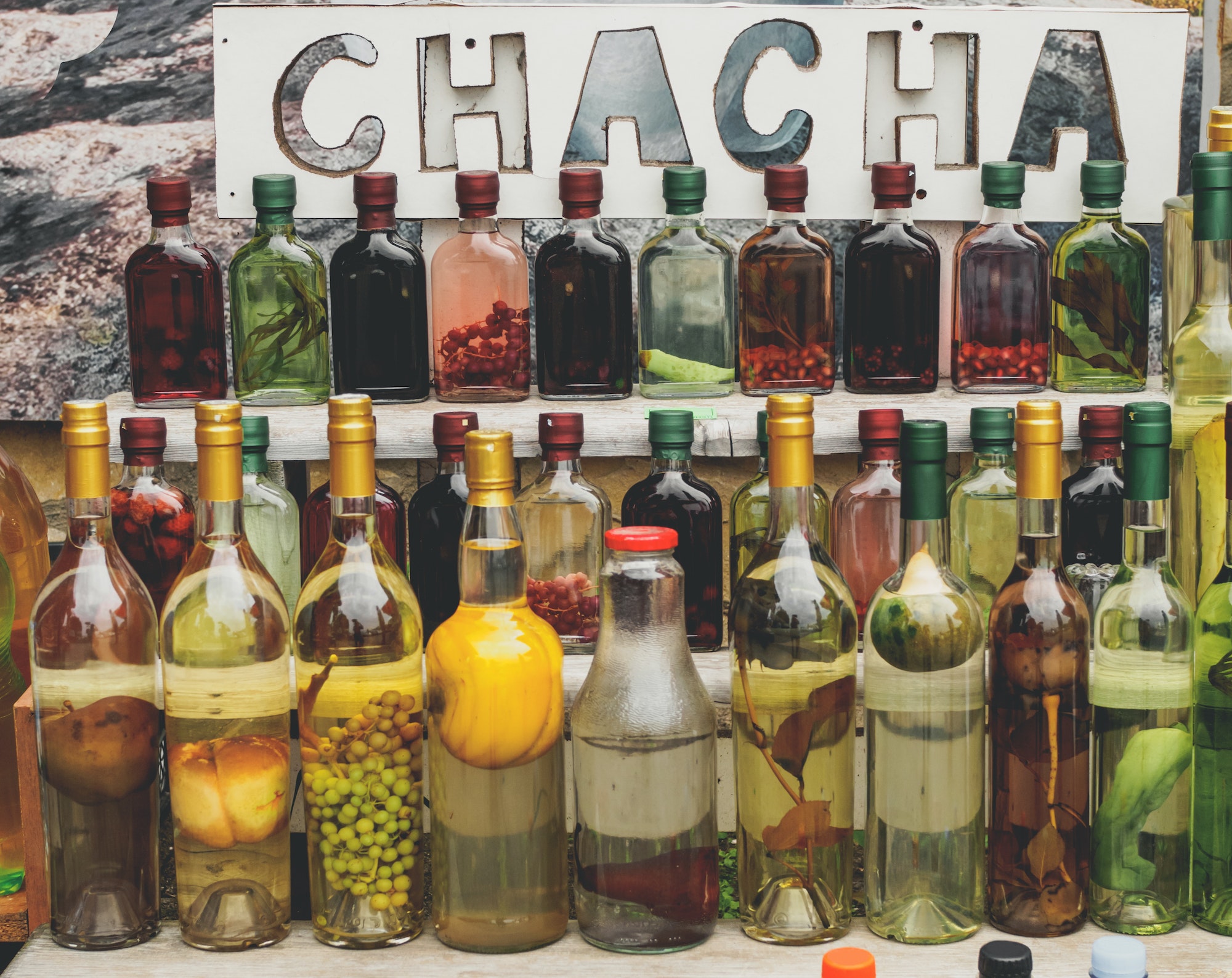 traditional georgian alcohol drink chacha in bottles with different fruits and herbs selling at